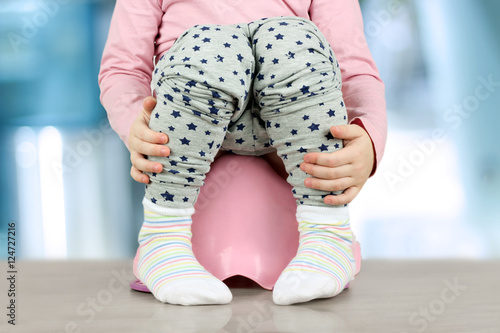 Foto Children's legs hanging down from a chamber-pot on a blue backgr