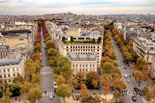 Aerial view over streets of Paris, France with trees in autumn colors lining sidewalks on sunny day.