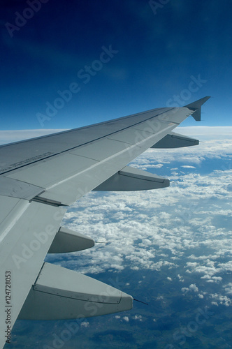 Aile d'avion en vol vue à travers un hublot passager, volets fermés