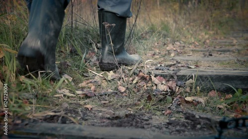 man with pitchfork goes along old railway