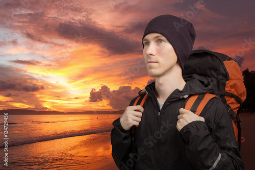 Young man with backpack on the background of sea sunset.