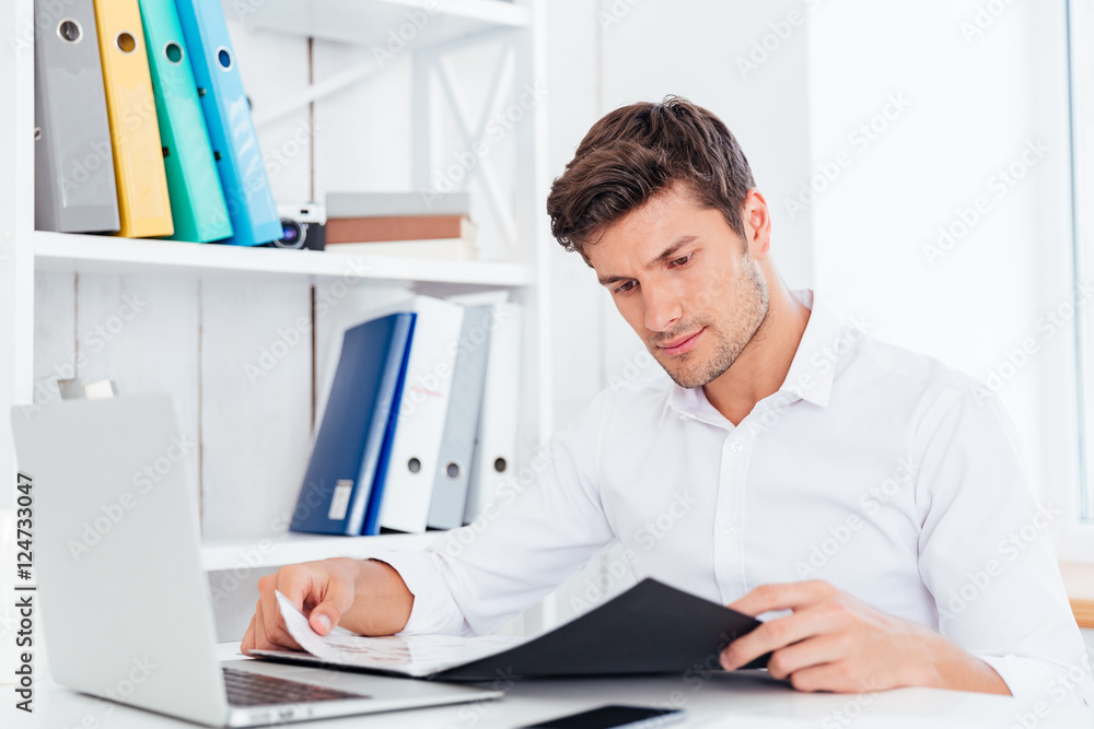 Serious businessman working with documents in folder at workplace Serious businessman working with documents in folder at workplace