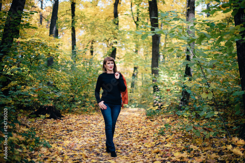 girl walking in the autumn yellow wood, maple grove