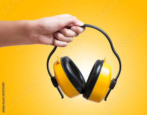 Yellow protective ear muffs in hand