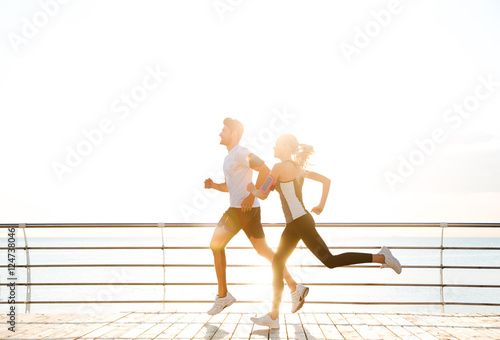 Young sporty couple running over wooden pier © Drobot Dean