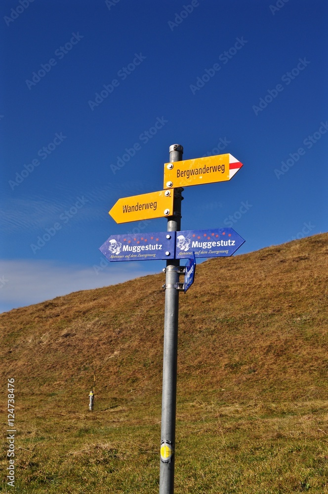 Gelber Wegweiser für Wanderer am Wanderweg in den Schweizer Alpen vor blauem Himmel Gelber Wegweiser für Wanderer am Wanderweg in den Schweizer Alpen vor blauem Himmel