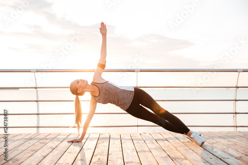 Sporty fitness woman doing planking yoga exercises outdoors
