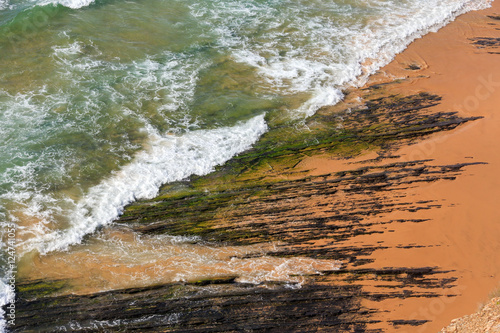 Rock formations on beach and surf wave.