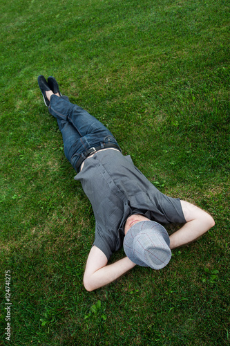 businessman lying in a field on green grass with the hat over his face. Passive income