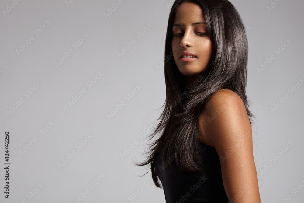 brunette woman with straight hair on grey watching down brunette woman with straight hair on grey watching down