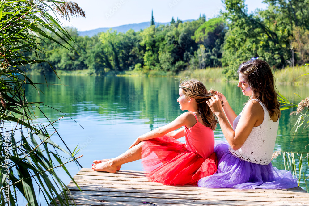 Girls relaxing next to lake.