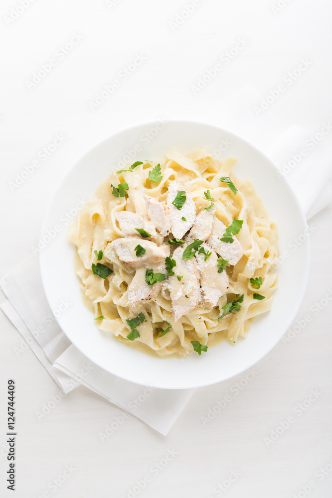 Pasta fettuccine alfredo with chicken, parmesan and parsley on white background top view. Italian cuisine. Pasta fettuccine alfredo with chicken, parmesan and parsley on white background top view. Italian cuisine.