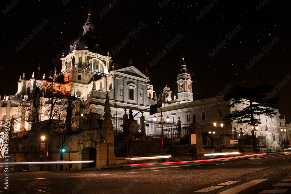 Long exposure night view of Almudena Cathedral in Madrid, Spain. With beams of lights marked cars.