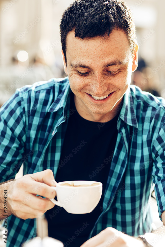 Young man drinking coffee in a sidewalk cafe Young man drinking coffee in a sidewalk cafe