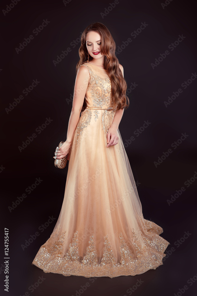 Attractive brunette woman in golden long dress isolated on black Attractive brunette woman in golden long dress isolated on black