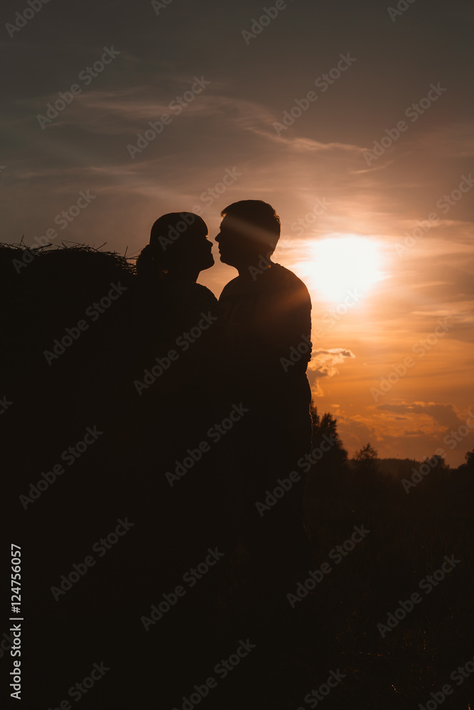 silhouettes of man and woman on a background  the sun  field