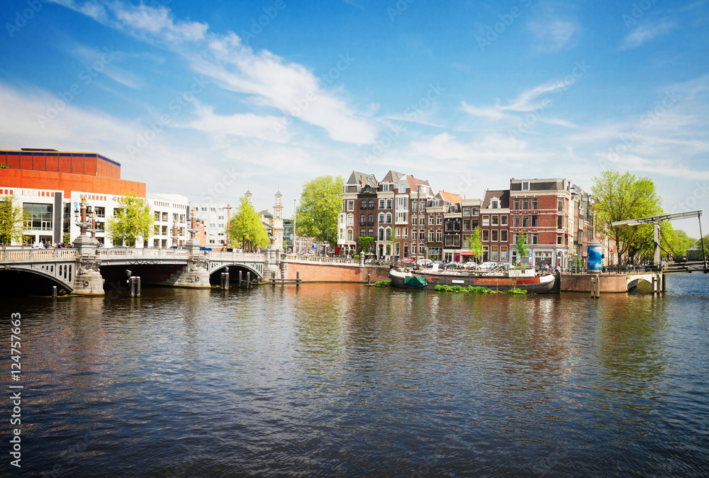 Blue bridge of Amsterdam on Amstel river at sunnu spring day, Netherlands, retro toned