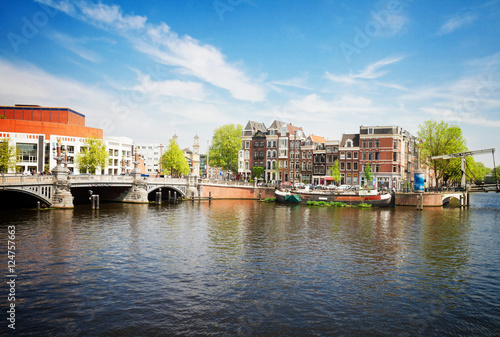 Blue bridge of Amsterdam on Amstel river at sunnu spring day, Netherlands, retro toned