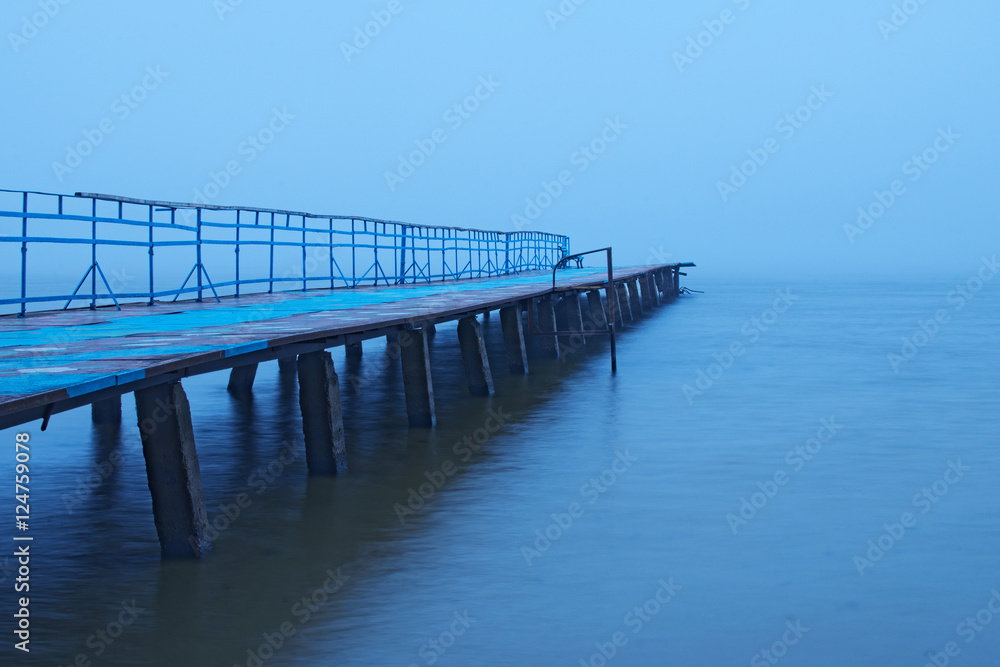 Misty morning on the lake. Old abandoned pier goes into the fog