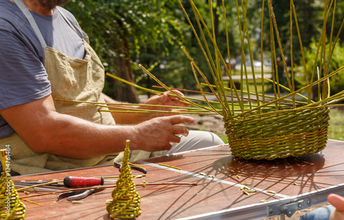 A craftsman weaves a basket from a rod photo