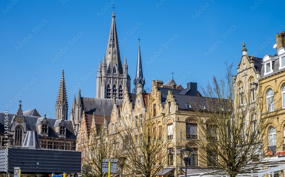 Characteristic Flemish high pitch roof lines in the main square of Ypres (Ieper), Belgium, with the spire of St. Martin's Cathedral in the background