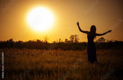 Silhouette of dancing young girl in dress against the sunset sky