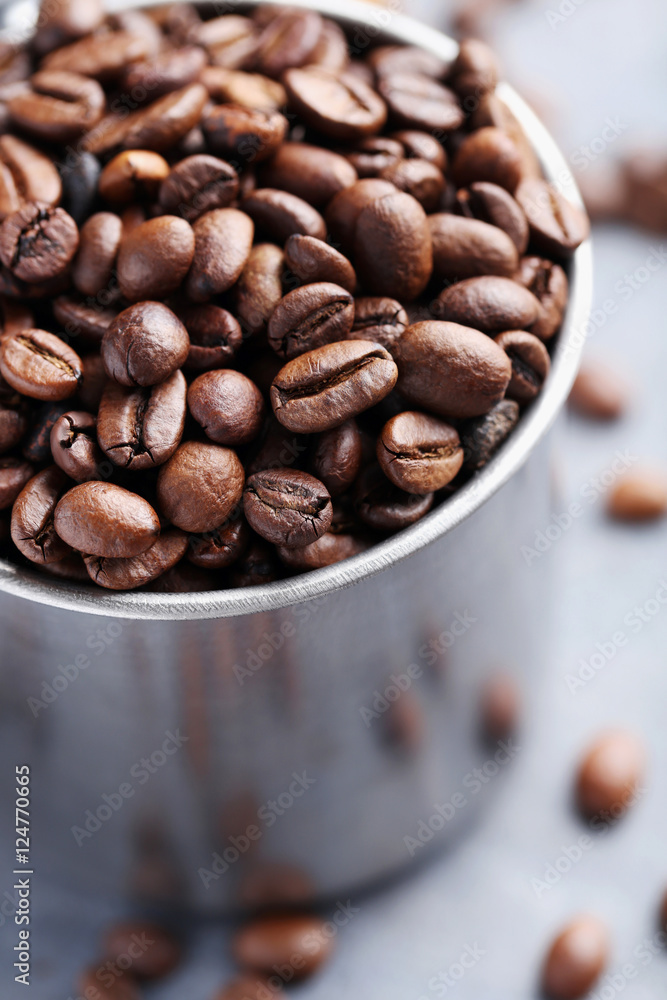 Fototapeta premium Roasted coffee beans in mug on grey table