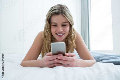 Woman lying on bed and using mobile phone on bed
