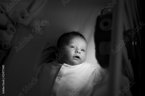 Baby fascinated by light as she looks at a nursery toy in the dark