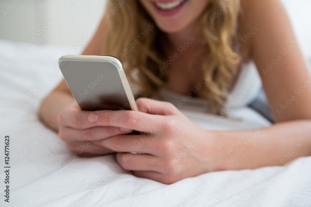 Woman lying on bed and using mobile phone on bed Woman lying on bed and using mobile phone on bed
