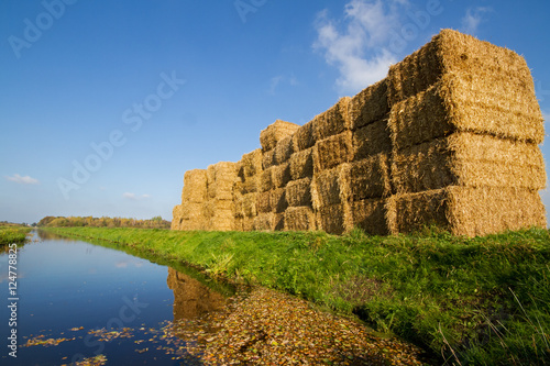 Stacked straw bales on the banks of a canal