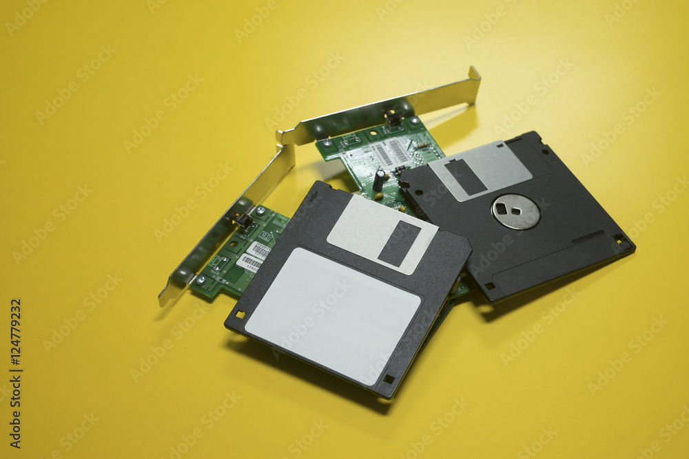 Floppy disk magnetic computer and electronic circuit board put on a yellow desk background.selective focus Floppy disk magnetic computer and electronic circuit board put on a yellow desk background.selective focus