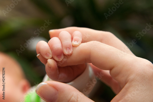 The baby clings to his mother's finger photo