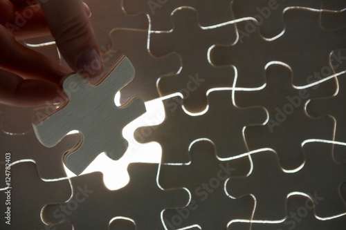 Woman placing missing piece in Jigsaw puzzle