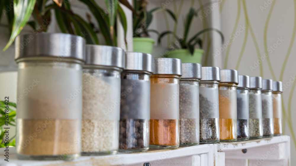 Spices, seasonings in small glass jars on wooden box Spices, seasonings in small glass jars on wooden box