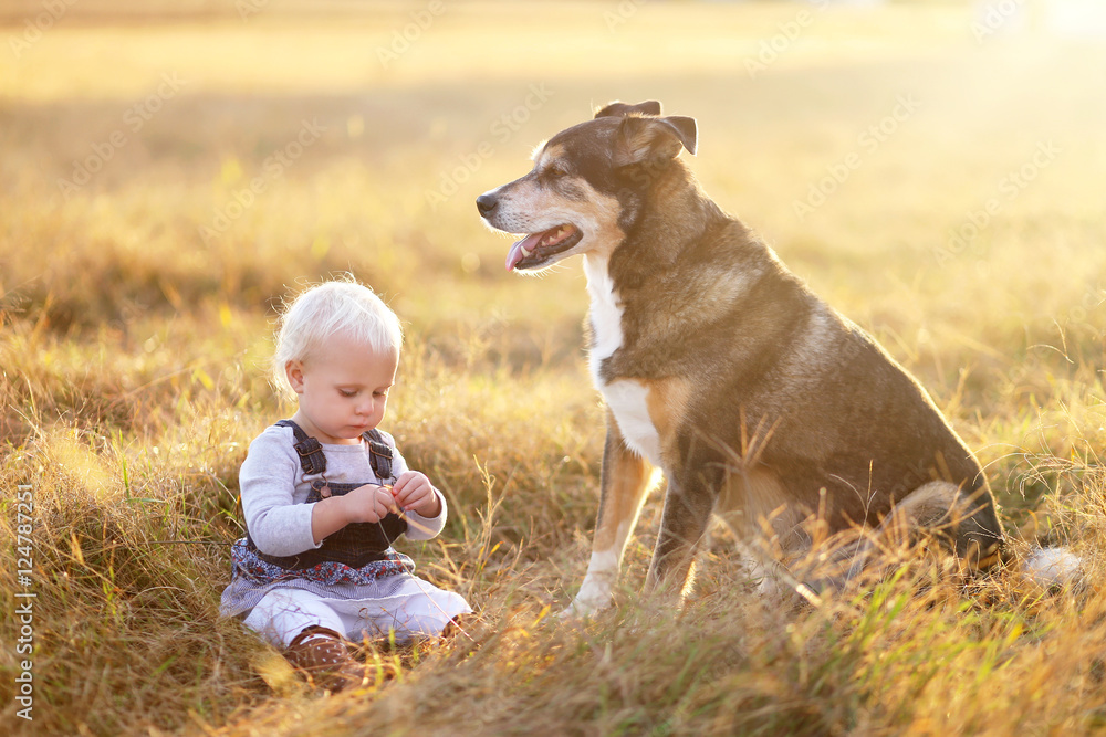 Toddler Girl Sitting Outside at Dusk with Pet Dog