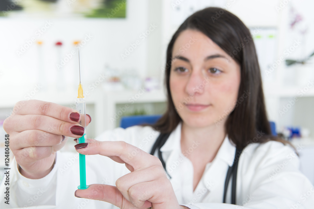 Junge Ärztin zieht Spritze mit Impfstoff auf Junge Ärztin zieht Spritze mit Impfstoff auf