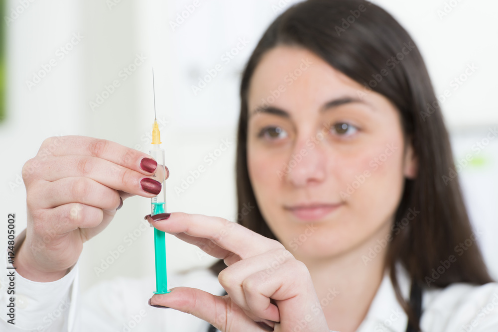 Junge Ärztin zieht Spritze mit Impfstoff auf Junge Ärztin zieht Spritze mit Impfstoff auf