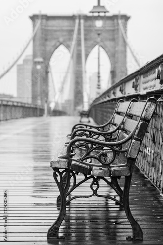 Brooklyn Bridge with no people on a rainy day with a bench in the foreground