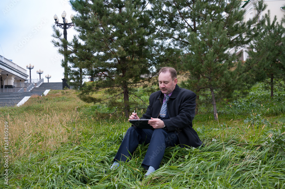 Obraz premium Man working with tablet on nature 
