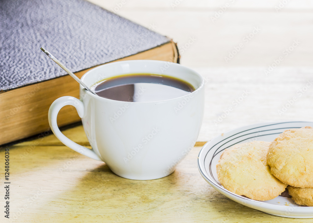 a cup of black coffee with cookies and book on wooden table a cup of black coffee with cookies and book on wooden table