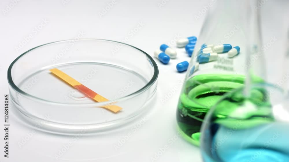 Drop acid liquid on a litmus strip in petri dish, ph paper, chemical measurement Drop acid liquid on a litmus strip in petri dish, ph paper, chemical measurement
