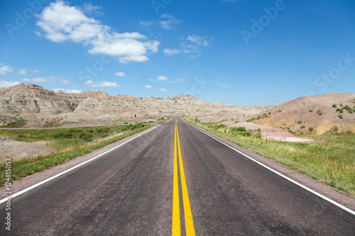 A road cutting through rolling hills in the Badlands of South Dakota on a summer day.  