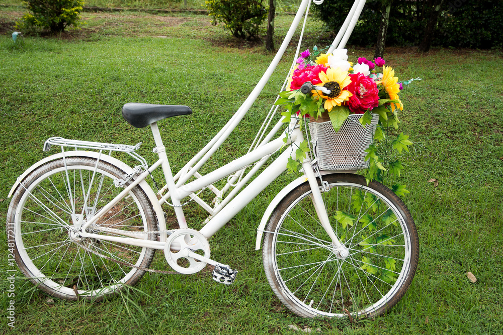  bicycle with basket full of flowers standing in the  grass