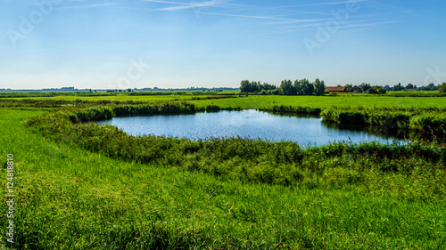 A pond in flat land of a farmers field near the Veluwemeer at the town of Nijkerk in the netherlands