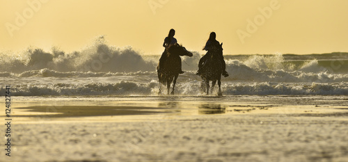 Horse riding on the beach at sunset