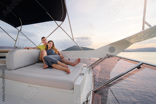 Romantic vacation and luxury travel. Young loving couple sitting on the sofa on the modern yacht deck. Sailing the sea. © luengo_ua
