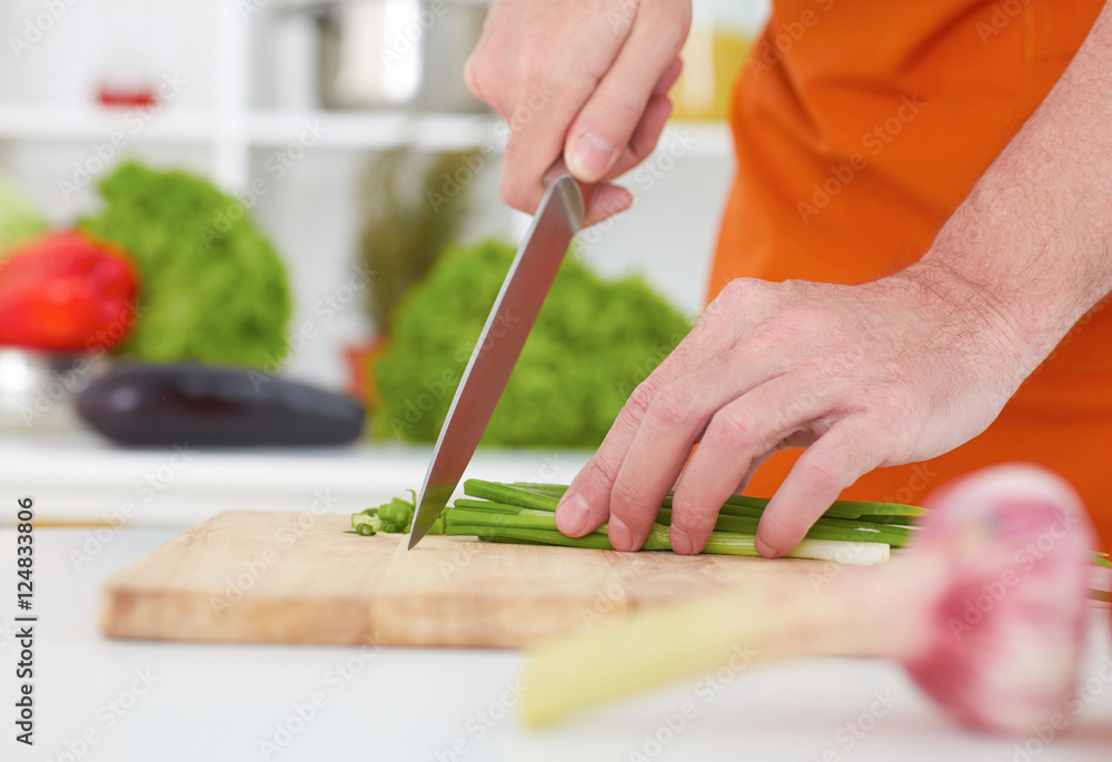 Close up of unrecognizable man chopping green onion with kitchen knife on cutting board. Healthy eating, dieting, slimming and weigh loss concept. Close up of unrecognizable man chopping green onion with kitchen knife on cutting board. Healthy eating, dieting, slimming and weigh loss concept.