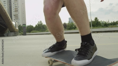 SLOW MOTION CLOSE UP: Extreme skateboarder jumping tricks on sunny city street photo