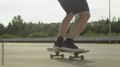 SLOW MOTION CLOSE UP DOF: Skateboarder jumping and doing a kickflip in a city photo